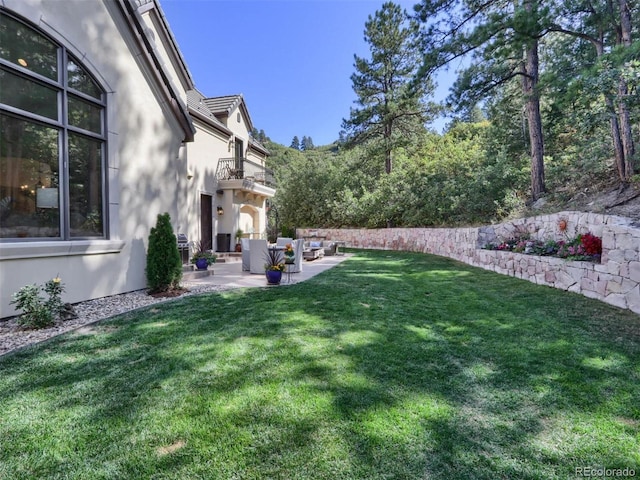 view of yard with an outdoor living space, a patio, and a balcony