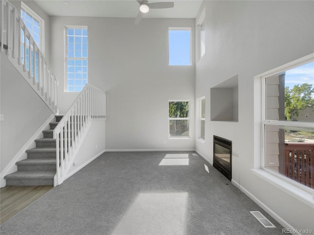 unfurnished living room with carpet floors, ceiling fan, and a wealth of natural light