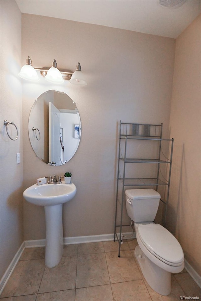 bathroom featuring tile patterned flooring, baseboards, a sink, and toilet