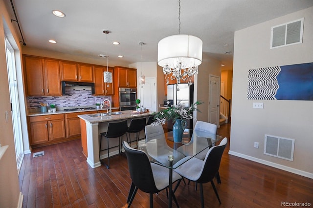 dining space featuring dark wood-style floors, recessed lighting, visible vents, and an inviting chandelier