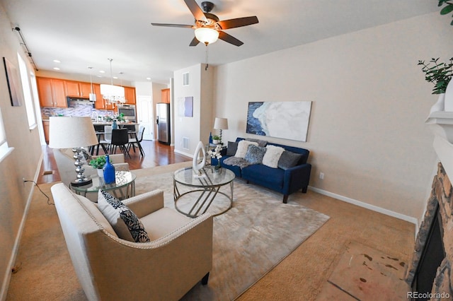 living room with visible vents, a fireplace, a ceiling fan, and baseboards