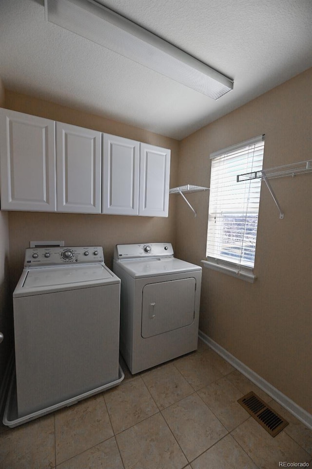 laundry area featuring cabinet space, light tile patterned floors, baseboards, visible vents, and independent washer and dryer