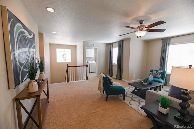 sitting room featuring a textured ceiling, light carpet, an upstairs landing, baseboards, and washer / clothes dryer