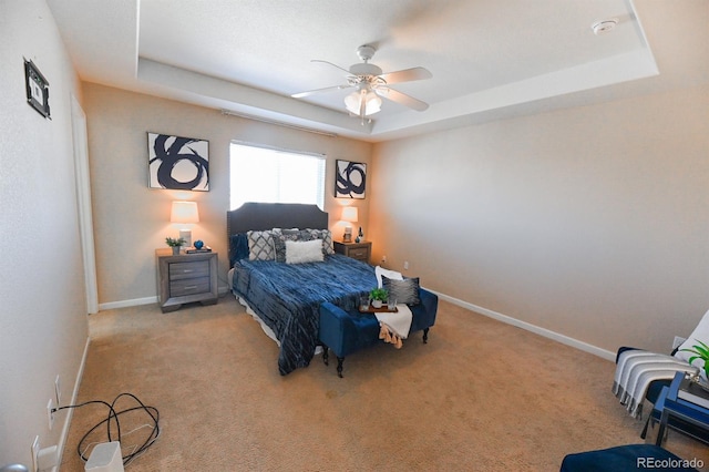 carpeted bedroom with baseboards, a raised ceiling, and a ceiling fan