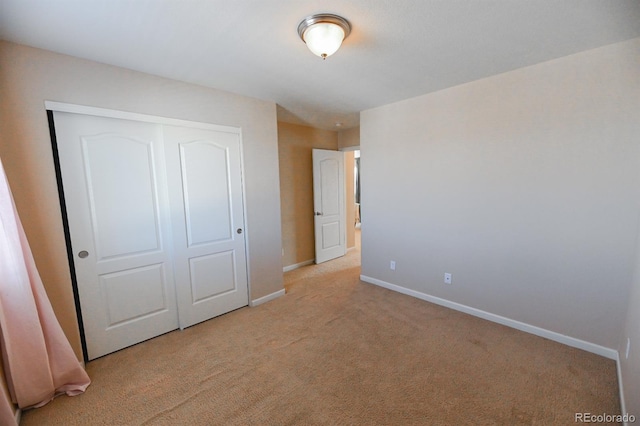 unfurnished bedroom featuring a closet, baseboards, and carpet flooring