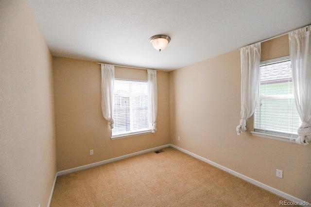 unfurnished room with light carpet, plenty of natural light, visible vents, and baseboards