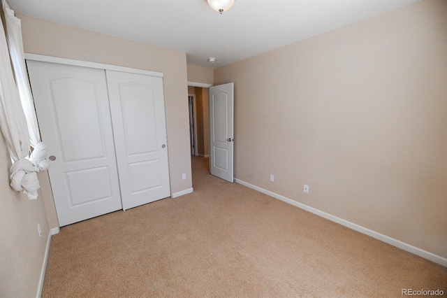 unfurnished bedroom with carpet, a closet, and baseboards