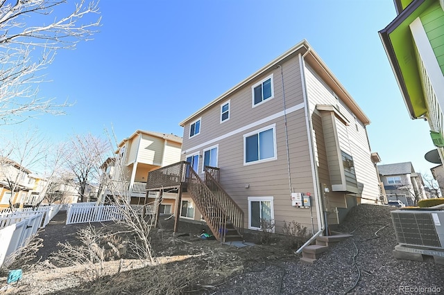 rear view of house with central AC unit, fence, a deck, a residential view, and stairs