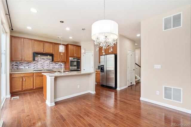 3565 E 141st Dr, Thornton, CO 80602 - kitchen with appliances with stainless steel finishes, brown cabinets, wood finished floors, backsplash, and recessed lighting