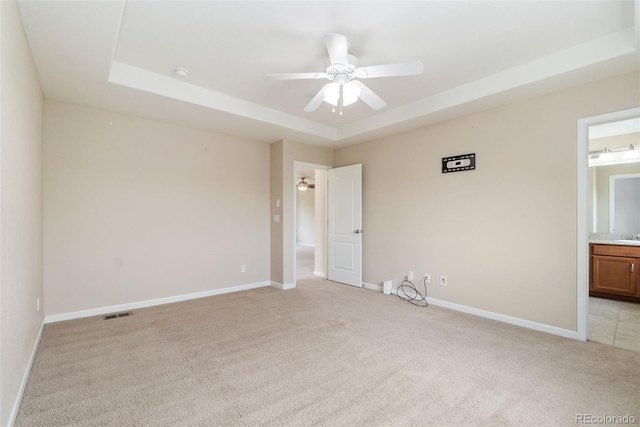 3565 E 141st Dr, Thornton, CO 80602 - unfurnished bedroom with light carpet, a tray ceiling, baseboards, connected bathroom, and a sink