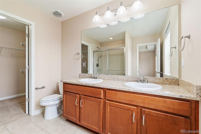3565 E 141st Dr, Thornton, CO 80602 - bathroom with double vanity, a shower stall, a walk in closet, toilet, and tile patterned floors