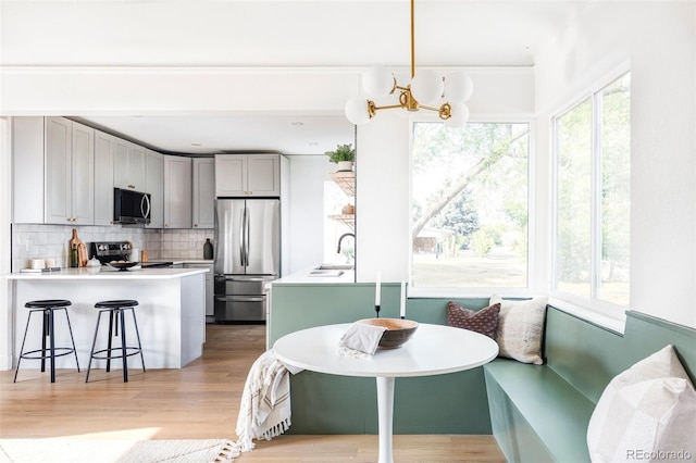 kitchen with breakfast area, decorative backsplash, appliances with stainless steel finishes, a sink, and a peninsula