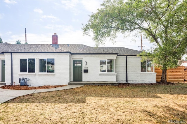 ranch-style house with brick siding, a chimney, a shingled roof, and fence