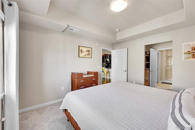 bedroom featuring carpet flooring, a raised ceiling, baseboards, ensuite bathroom, and visible vents