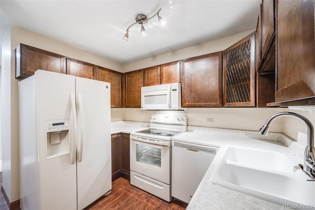 kitchen with a textured ceiling, dark hardwood / wood-style floors, sink, rail lighting, and white appliances