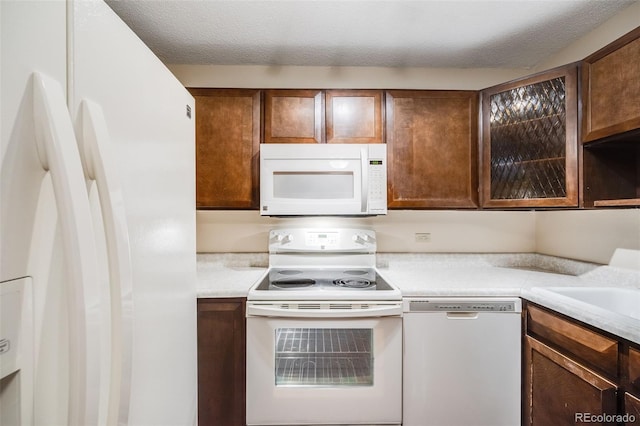 kitchen with a textured ceiling, sink, and white appliances