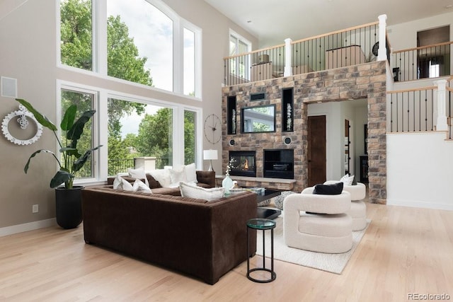 2535 W 115th Dr, Westminster, CO 80234 - living room featuring a stone fireplace, a towering ceiling, wood finished floors, and baseboards