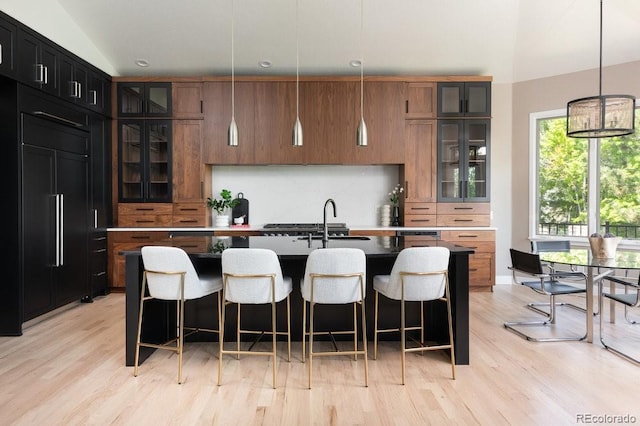 2535 W 115th Dr, Westminster, CO 80234 - kitchen featuring backsplash, light wood finished floors, a kitchen breakfast bar, a sink, and vaulted ceiling