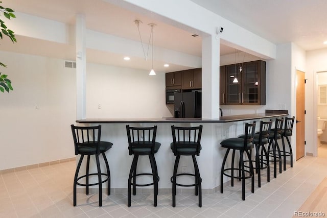 2535 W 115th Dr, Westminster, CO 80234 - kitchen featuring black fridge, dark brown cabinetry, a breakfast bar, recessed lighting, and a peninsula