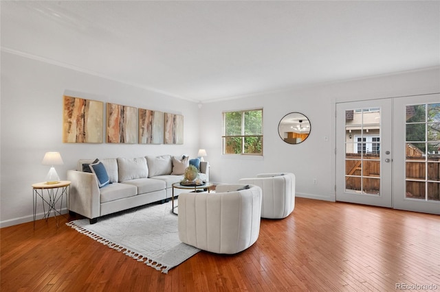 living area with hardwood / wood-style floors, crown molding, baseboards, and french doors