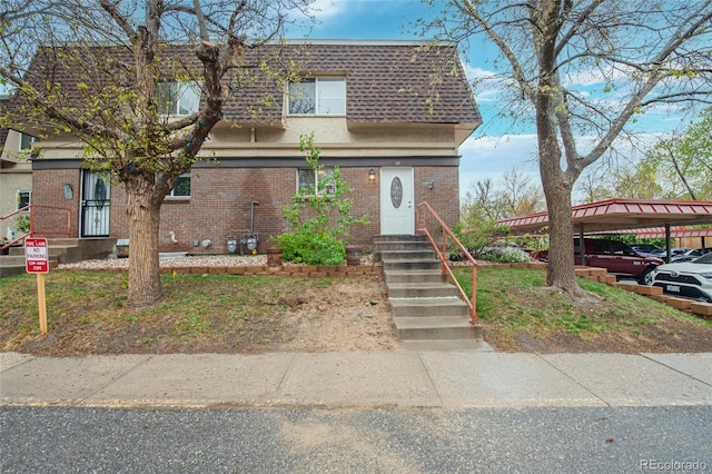 view of front of home with mansard roof, brick siding, and a shingled roof