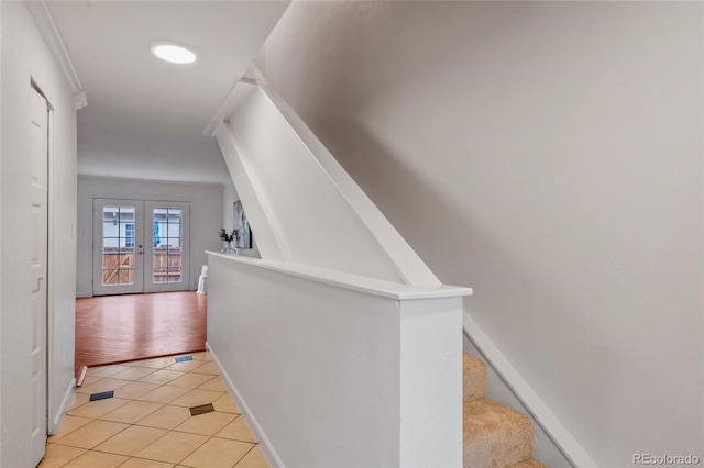 hall with french doors, light tile patterned floors, baseboards, and stairway