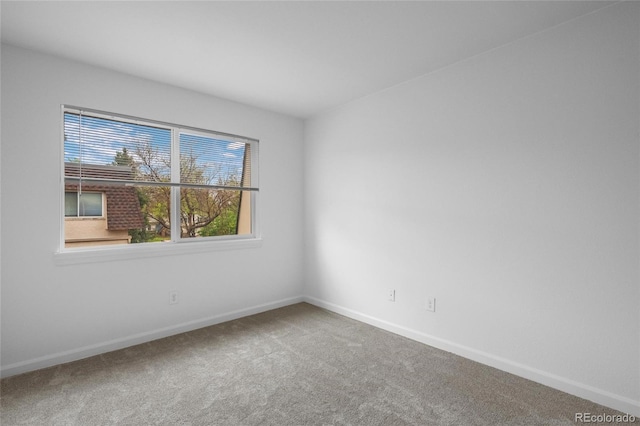 carpeted empty room featuring baseboards