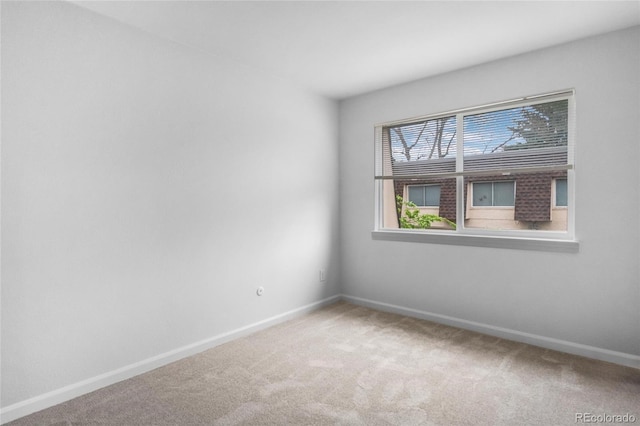 carpeted empty room featuring baseboards