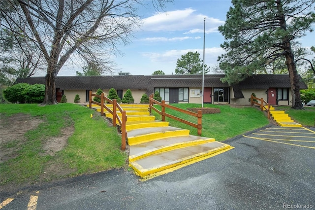 view of front of home with stucco siding, uncovered parking, and a front yard