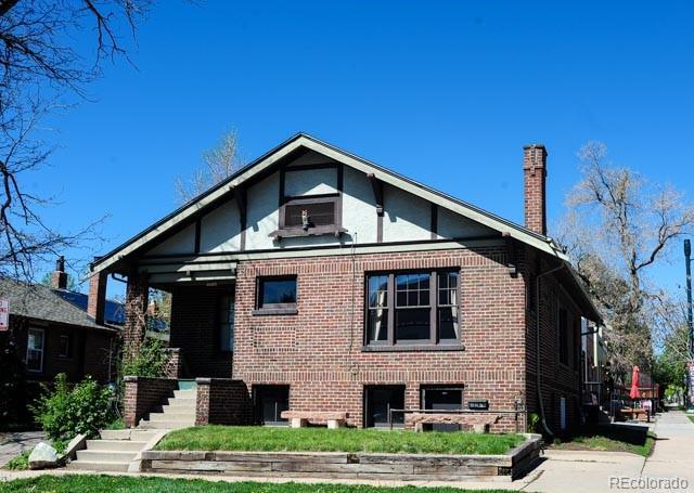 view of front facade with brick siding, a chimney, and stairs