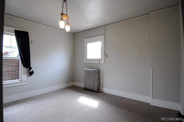 carpeted empty room featuring radiator heating unit and baseboards
