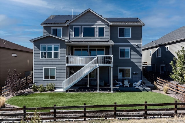 rear view of property featuring a lawn, solar panels, and a patio area