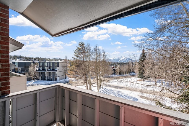 snow covered back of property featuring a mountain view