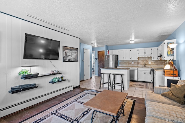 living room featuring a textured ceiling, baseboard heating, and light wood-type flooring