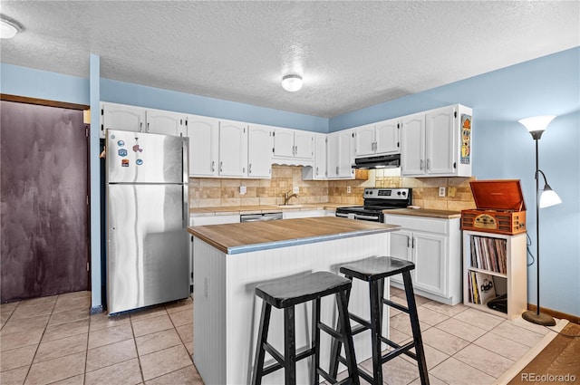 kitchen featuring a kitchen breakfast bar, under cabinet range hood, appliances with stainless steel finishes, and white cabinets