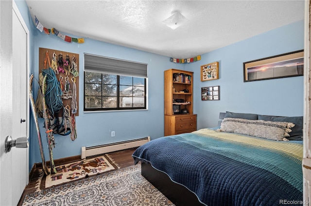 bedroom with baseboards, a textured ceiling, baseboard heating, and wood finished floors