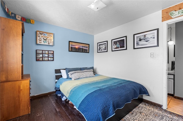 bedroom with dark wood finished floors, a textured ceiling, and baseboards