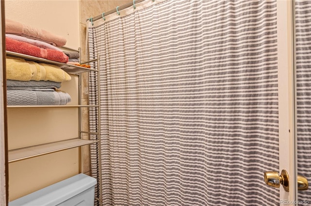 full bath featuring a shower with shower curtain and toilet