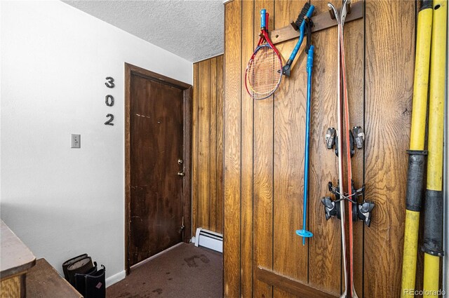 interior space featuring a baseboard heating unit, carpet, and a textured ceiling