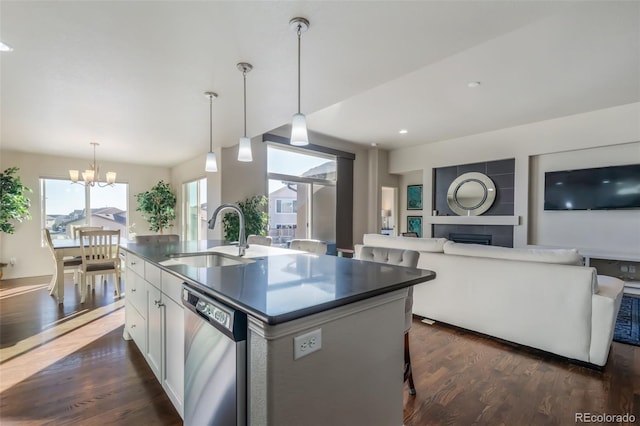 kitchen with decorative light fixtures, white cabinetry, dishwasher, sink, and a kitchen island with sink