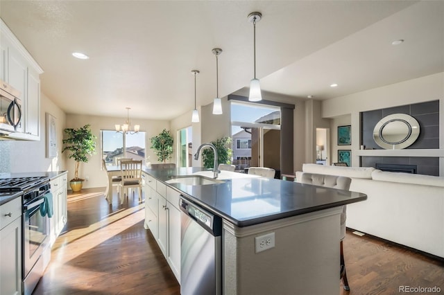 kitchen featuring sink, a kitchen island with sink, stainless steel appliances, white cabinets, and a kitchen bar