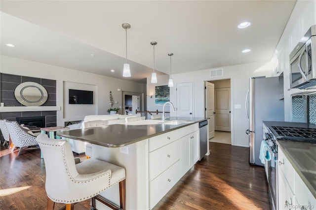 kitchen with a breakfast bar, sink, white cabinets, a kitchen island with sink, and stainless steel appliances