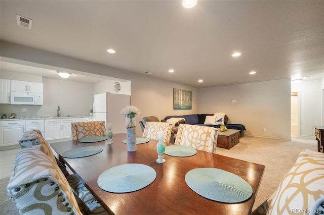 dining area with sink and light colored carpet