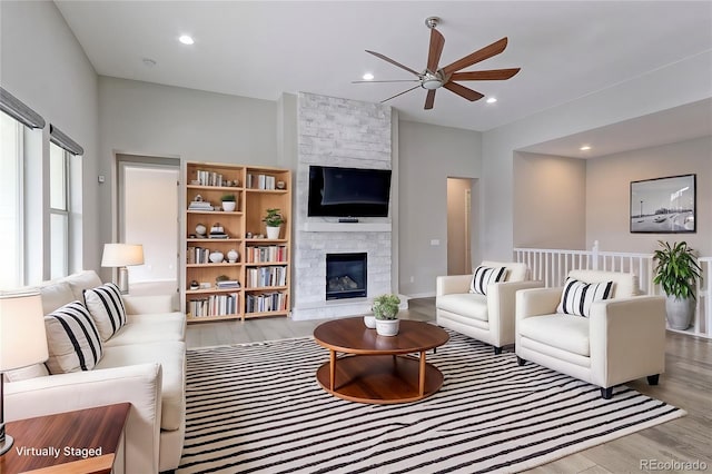 living room featuring a large fireplace, light hardwood / wood-style flooring, and ceiling fan