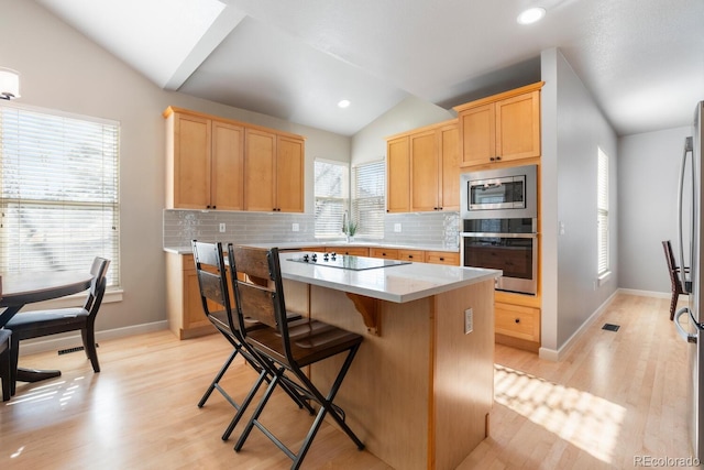 kitchen featuring appliances with stainless steel finishes, backsplash, a center island, and lofted ceiling