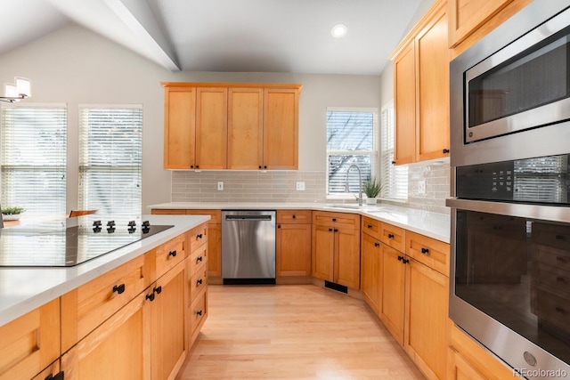 kitchen with light hardwood / wood-style flooring, stainless steel appliances, tasteful backsplash, and sink