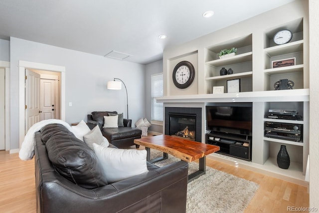 living room featuring light wood-type flooring and built in shelves