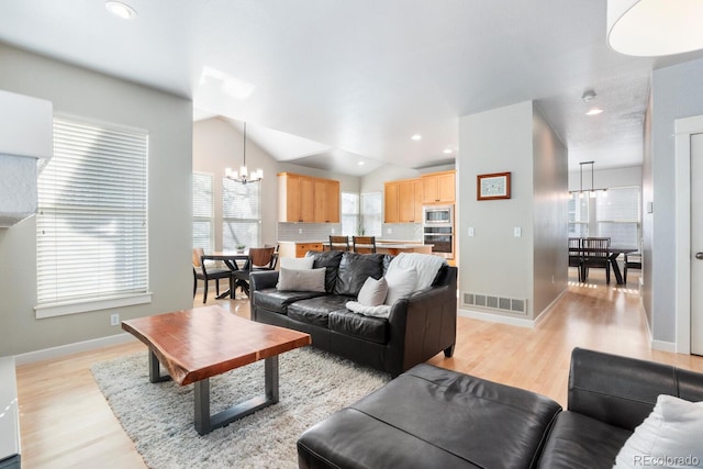 living room with light hardwood / wood-style floors, an inviting chandelier, and lofted ceiling