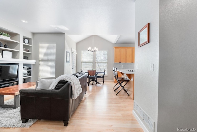 living room featuring light hardwood / wood-style floors, lofted ceiling, built in shelves, and a notable chandelier