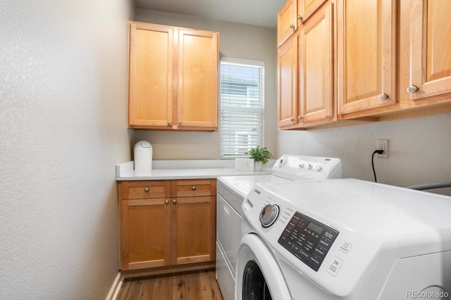 laundry room with washer and dryer, cabinets, and hardwood / wood-style floors